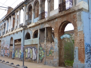 The facade hints at a once-splendid building, but now it is only a refuge for tangled weeds and feral cats
